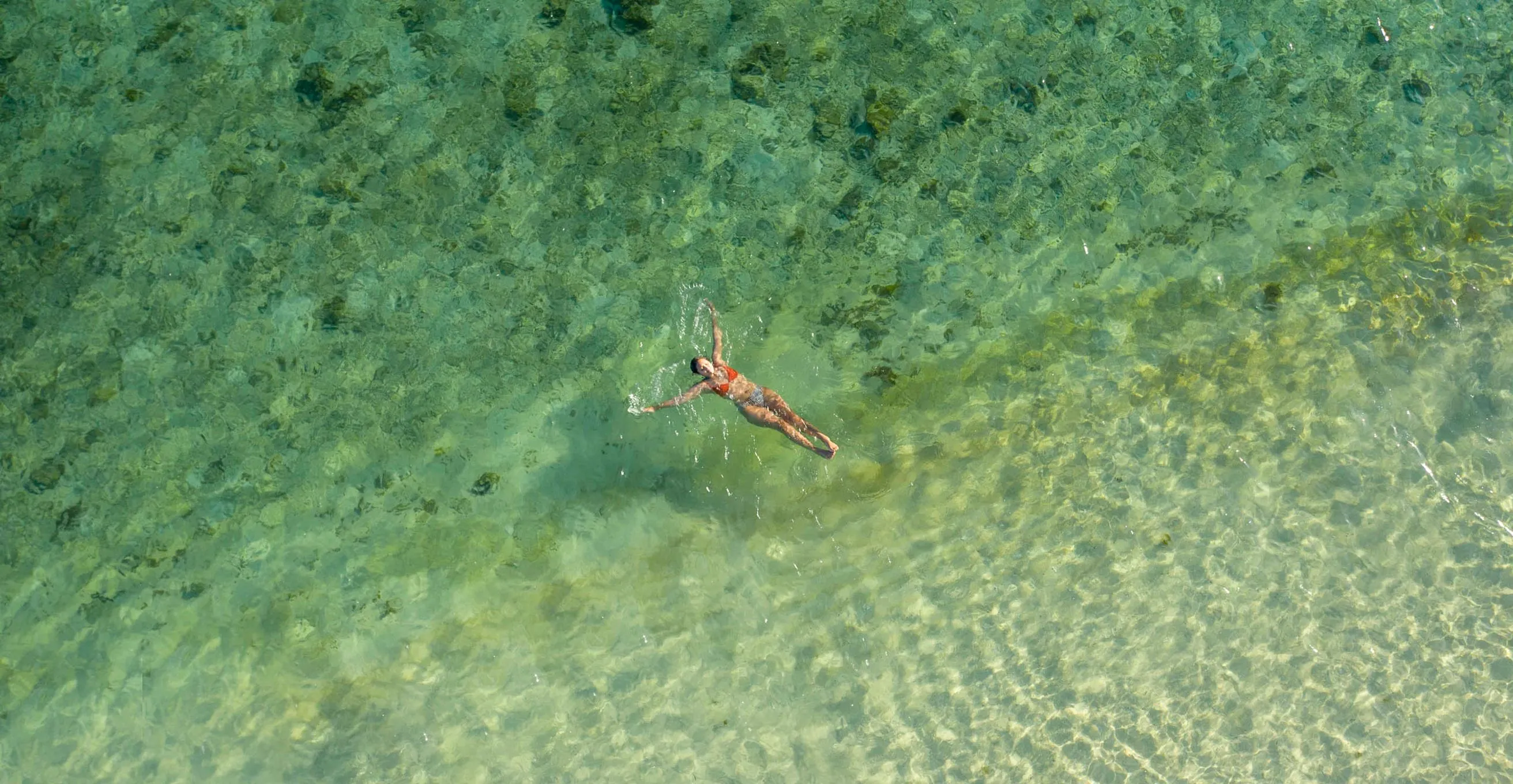 Drone view of a person floating in the water at Coron