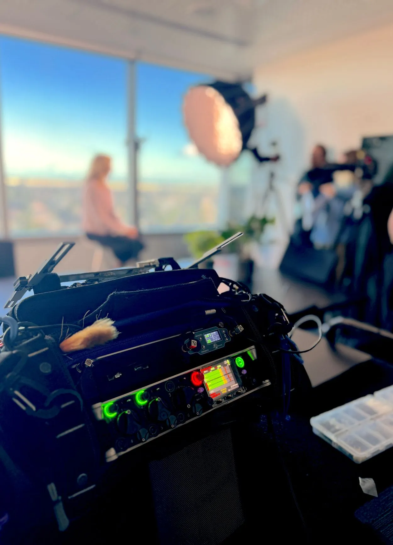 Sound bag and mixer in the foreground with an interview set up behind