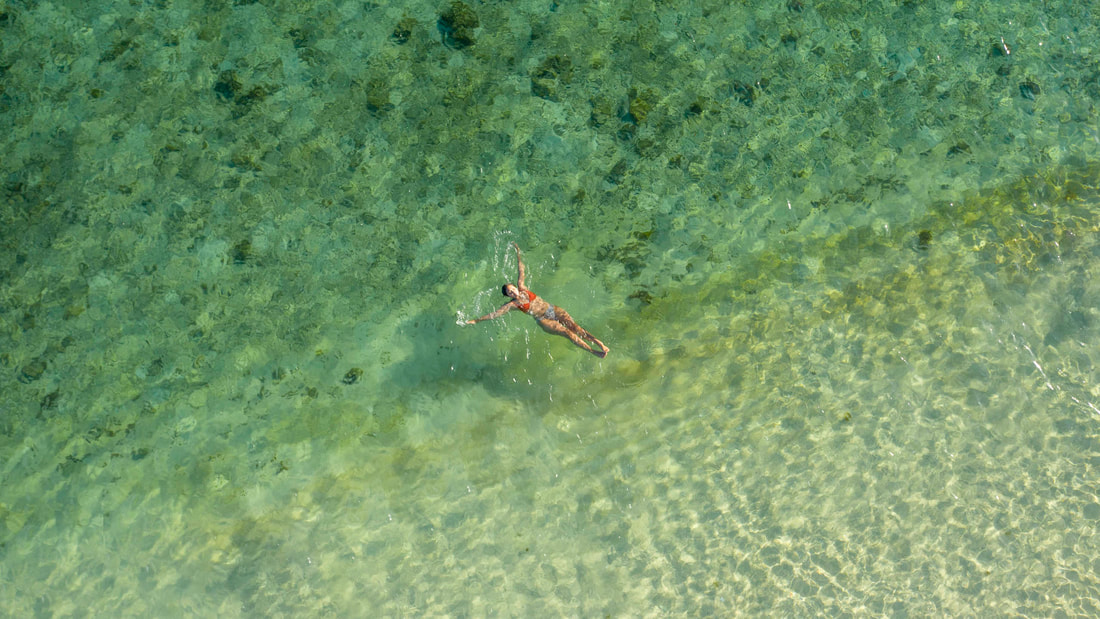 Drone Photography. Girl floating in clear water in Phillipines shot on DJI Mavic 2 Pro.